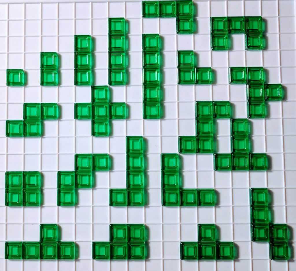 21 different blokus shapes, all in the color green, sitting on the blokus game board