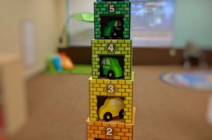 Stack of toy cardboard garages with wooden cars inside