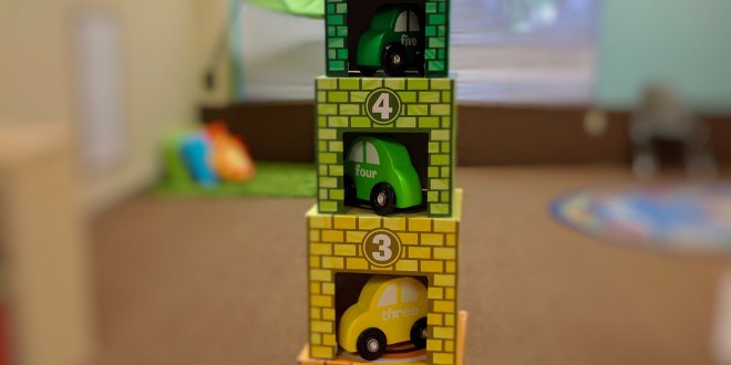 Stack of toy cardboard garages with wooden cars inside